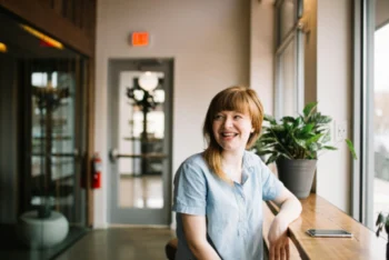 Woman smiling next to a plant